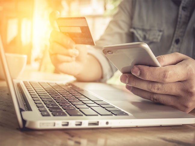 Person using smartphone and laptop for online shopping in Africa.
