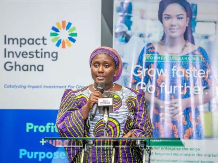 Woman speaking at impact investment event in Ghana promoting SDGs.