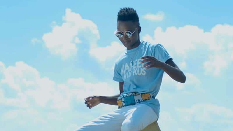 Gabiro Mtu Necessary singing "Kus Kus" outdoors under blue sky.