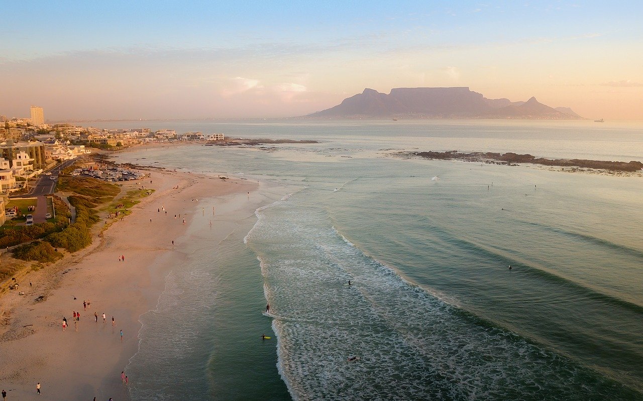 Beautiful coastal view of a quiet African beach with waves and distant mountains.