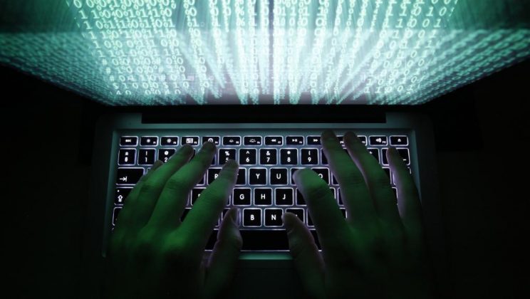 Hacker typing on a keyboard with digital code overlay, highlighting cybercrime issues in Africa.