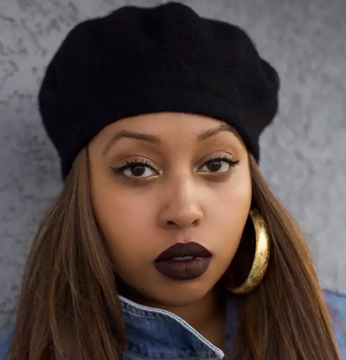 Portrait of a female African poet wearing a black beret and bold makeup.