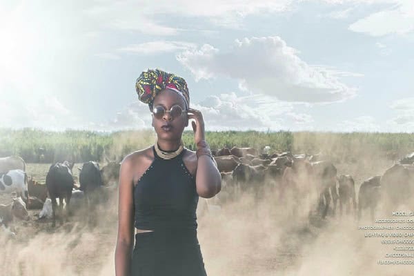 African woman entrepreneur with cattle in rural landscape.