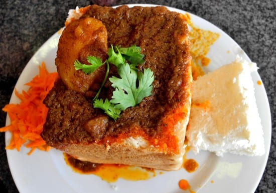 Vibrant African street food featuring a flavorful meat stew served with rice and vegetables.