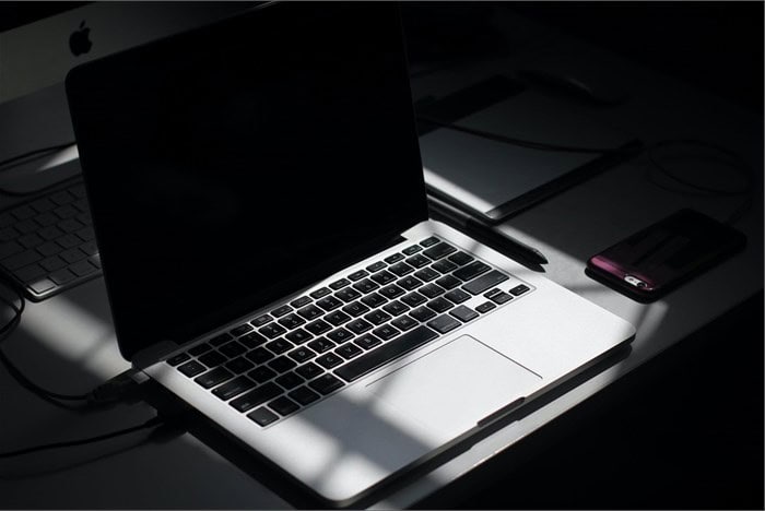 Laptop with charger on a dark desk, ready for work or backup power during load shedding.