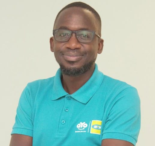 AYo Zambia representative smiling in a turquoise polo shirt with logos.
