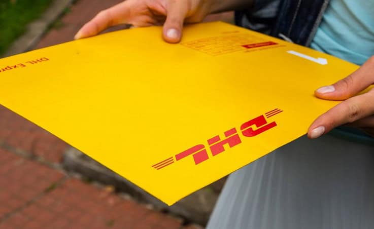 DHL courier holding a yellow package with red DHL logo in South Africa.
