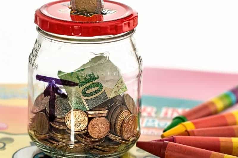 Money-saving jar filled with coins and banknotes for financial savings and budgeting tips.