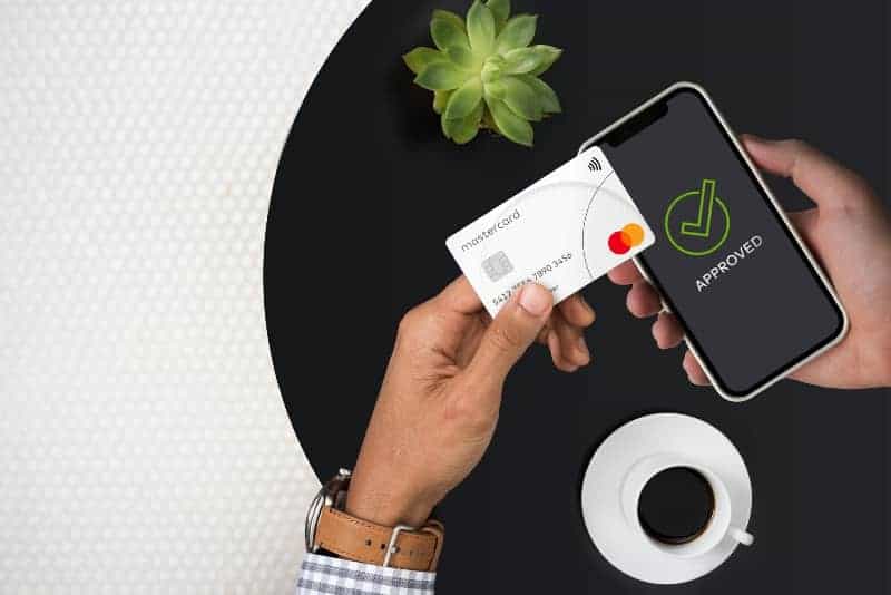 Person using phone to make contactless Mastercard payment with approved checkmark.
