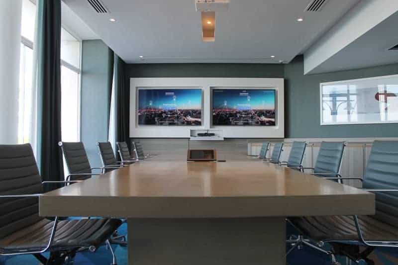 Conference room with dual screens and ergonomic chairs for corporate presentations.
