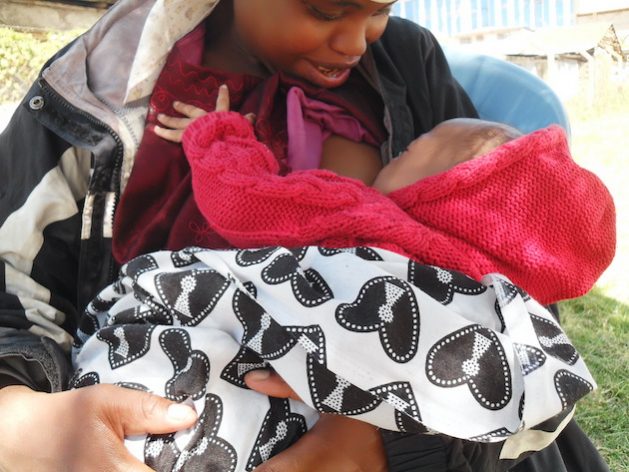 Child receiving breastfeeding support in Africa for improved health.