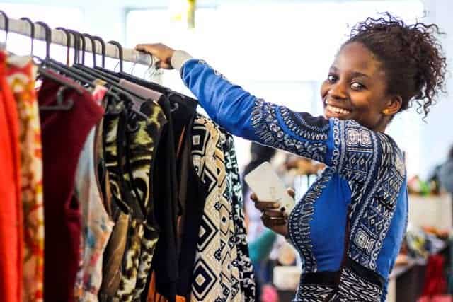Bright African woman shopping for clothing at local market.