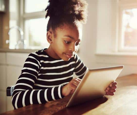 Young girl using a tablet to learn and explore digital technology at home.