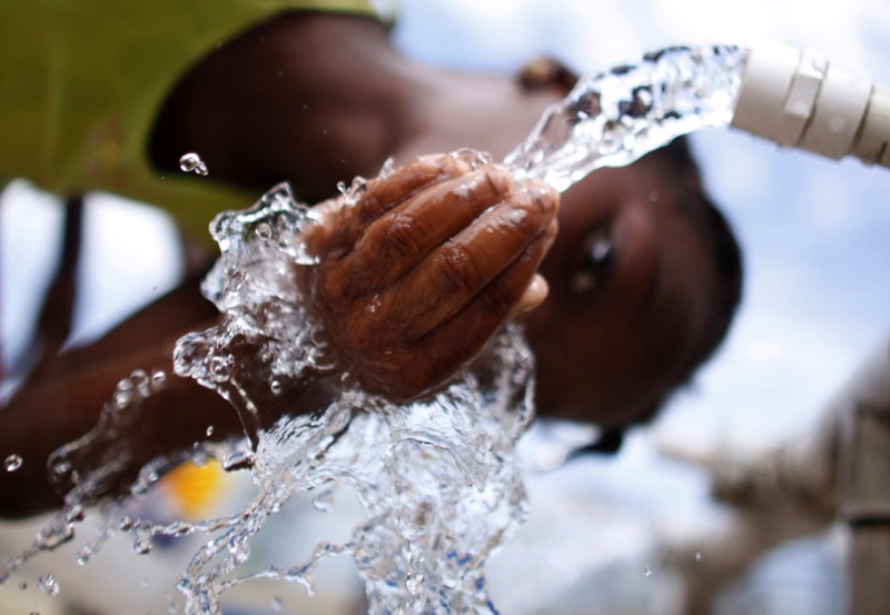 Woman collecting clean water from a tap in Africa for daily use.
