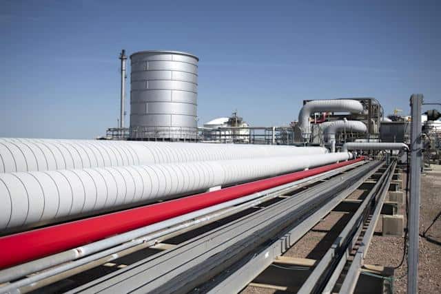 Oil pipeline infrastructure in Africa with storage tanks and industrial pipes.