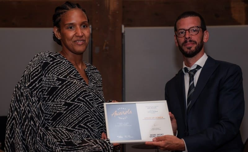 Two individuals exchanging an award at a sports event in Africa.