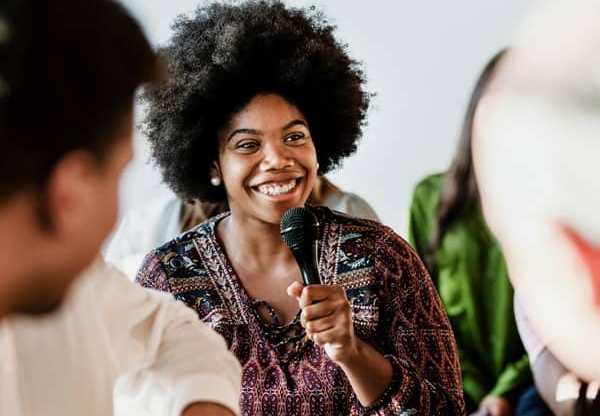 African woman speaking into a microphone at a discussion event.