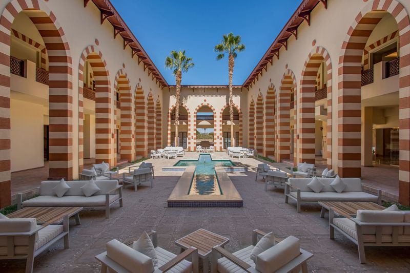 Elegant hotel courtyard with arches and palm trees in Africa.
