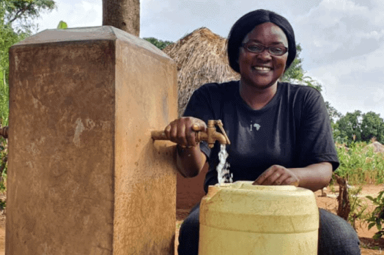 Woman installing a water tap in a rural African community for sustainable development.