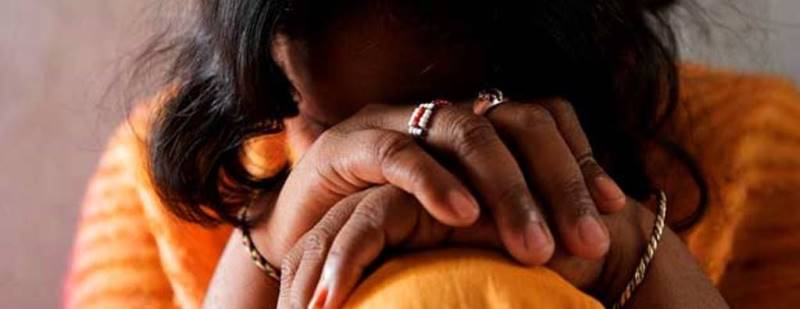 Woman covering her face, highlighting vulnerability amid climate change in Malawi.