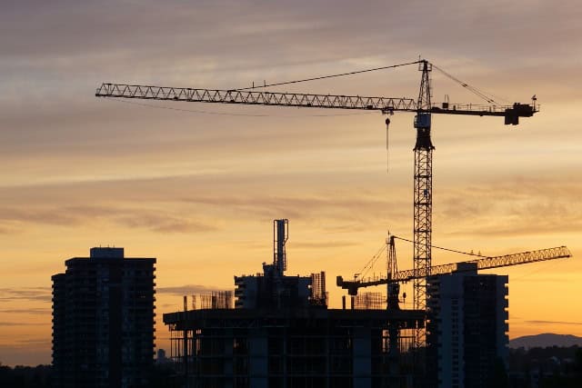 Construction cranes and buildings under development in Nigeria at sunset.