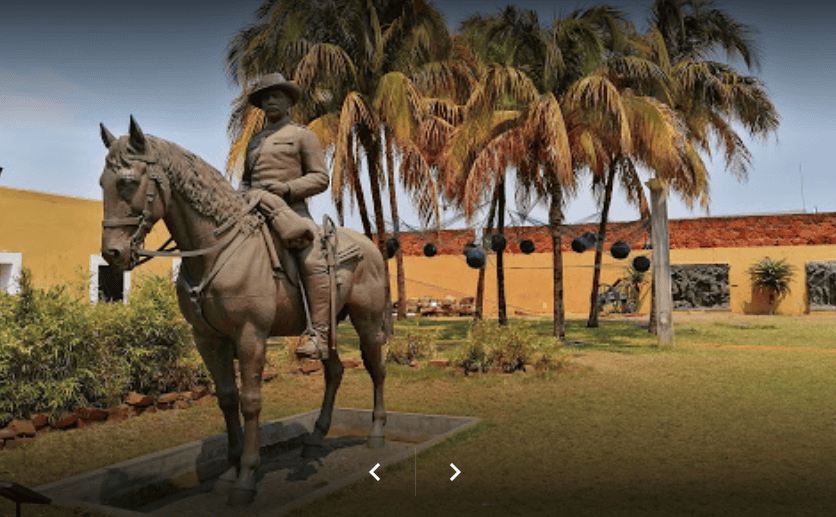 Statue of a rider on horseback surrounded by lush palm trees in Mozambique.