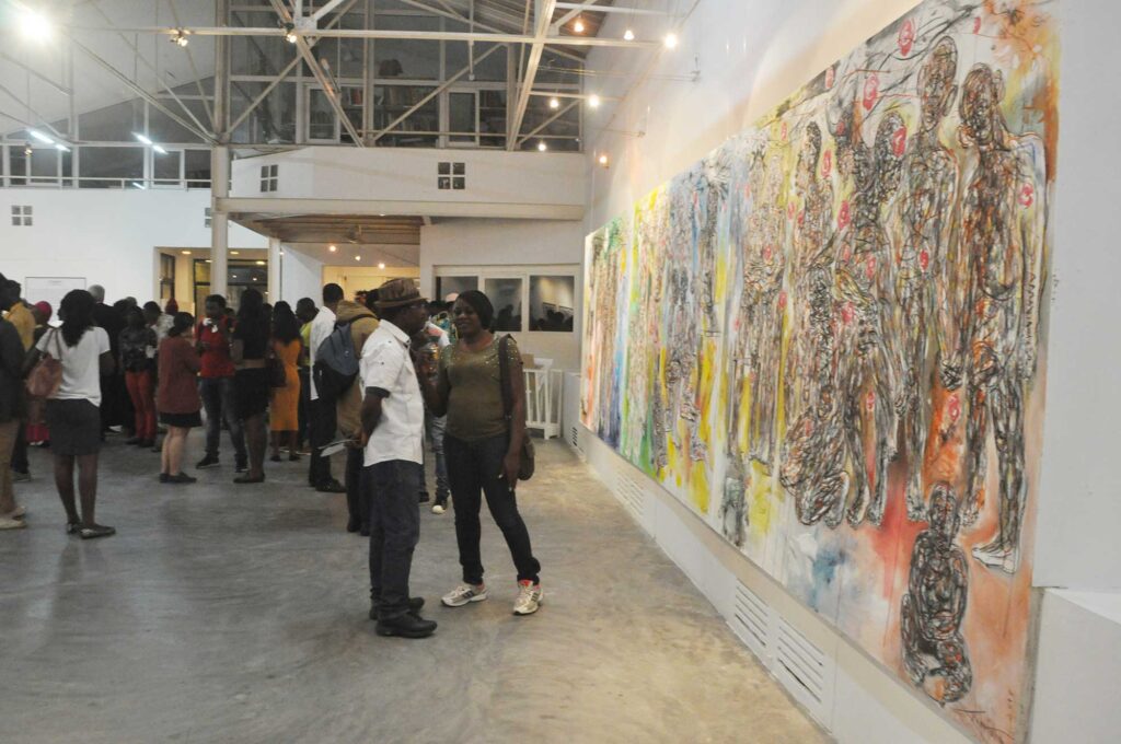 Visitors viewing contemporary artwork at a Cameroon art gallery.