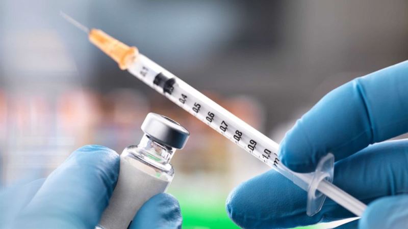 Vaccine vial and syringe being prepared for immunization.