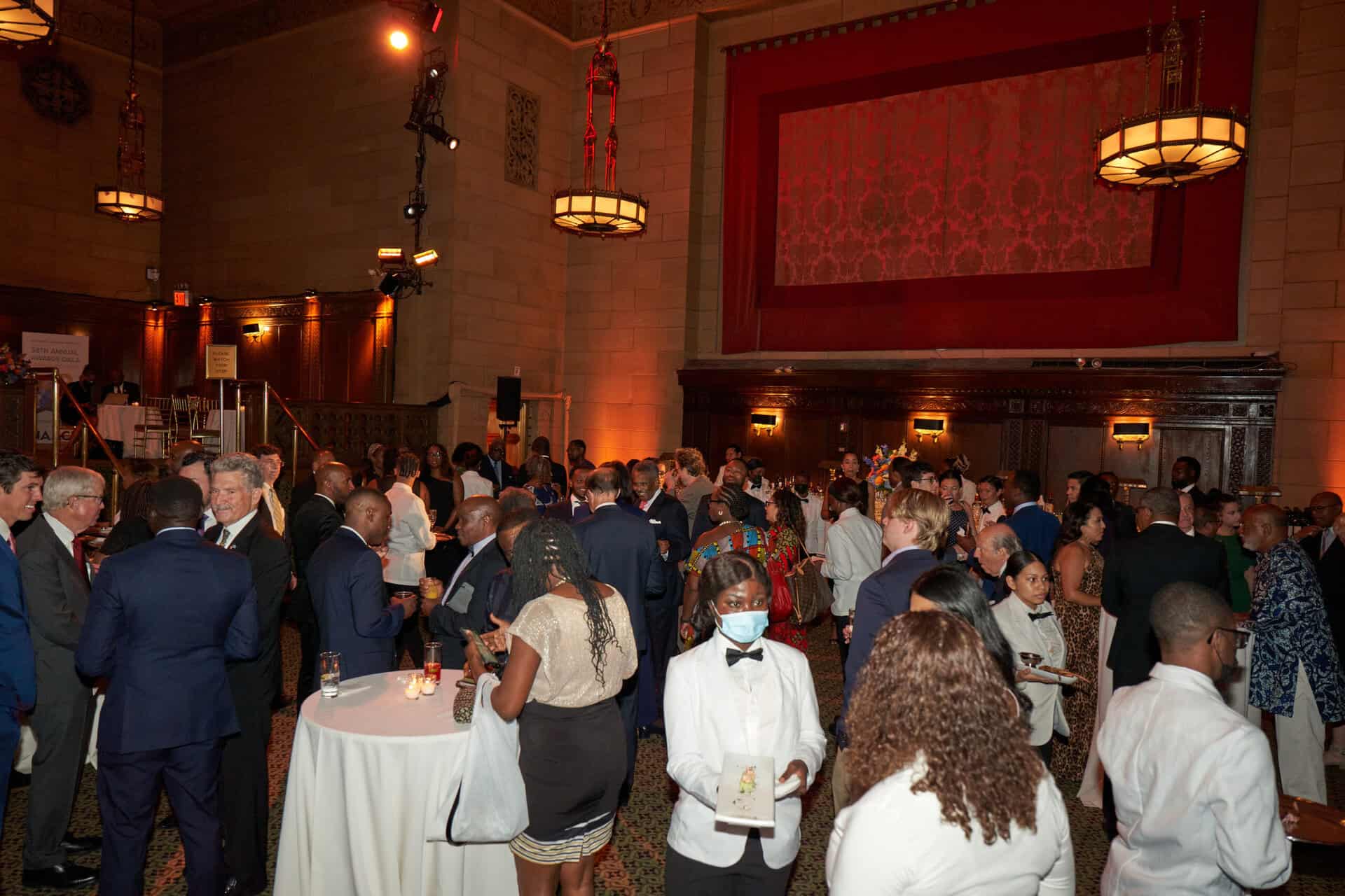 Elegant networking event with diverse attendees in formal attire at a grand hall.