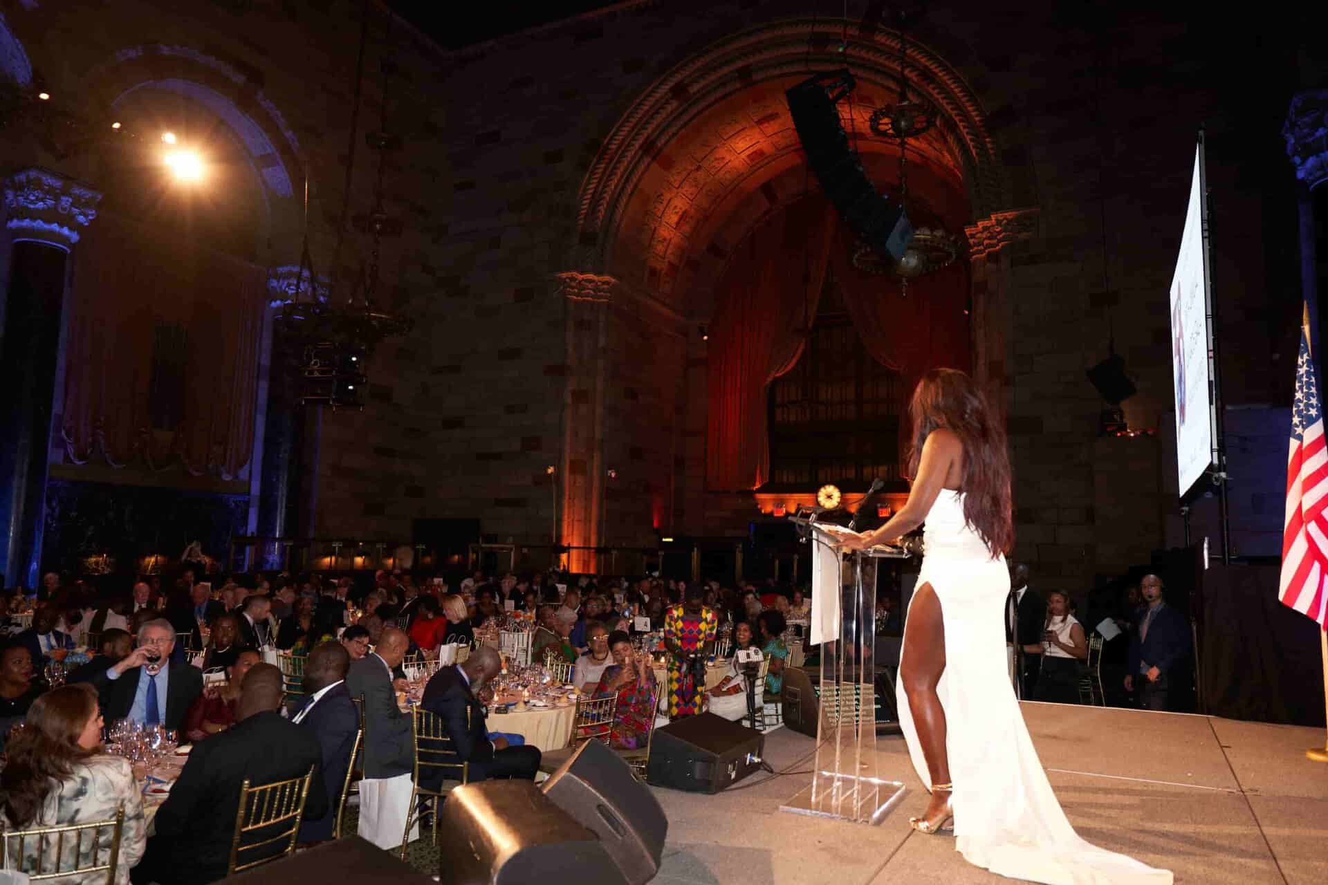 Elegant woman in white gown speaking at Africa.com event.