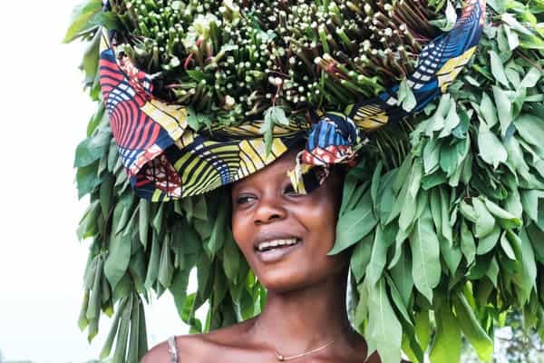 African woman wearing a headpiece made of leaves and plants for cultural celebration.