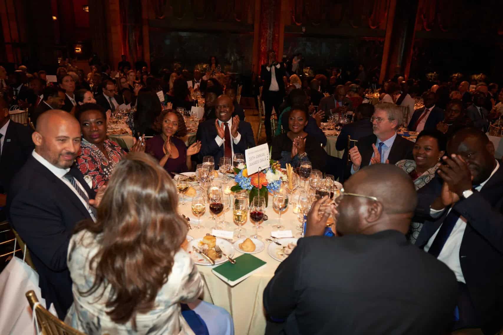Business professionals networking at an African event in a grand hall.