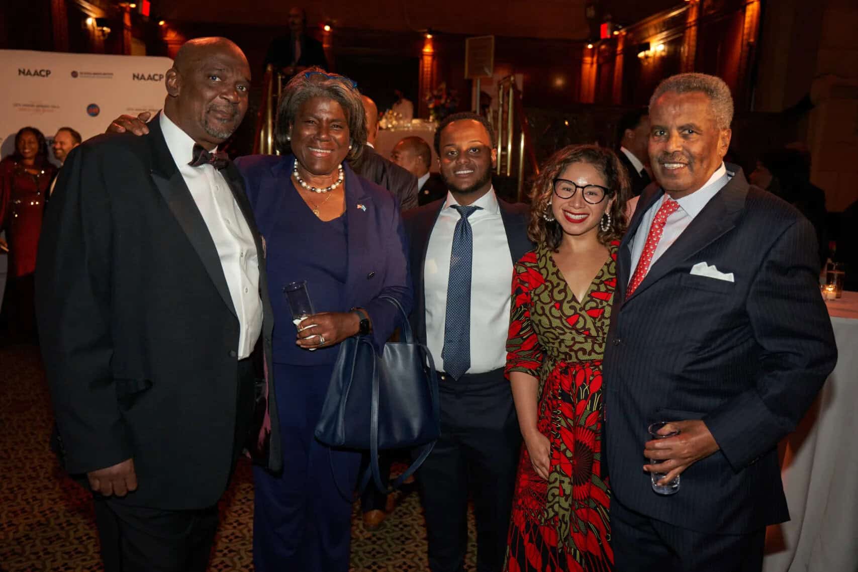 Elegant group of African professionals at a formal event, smiling and dressed in business attire.