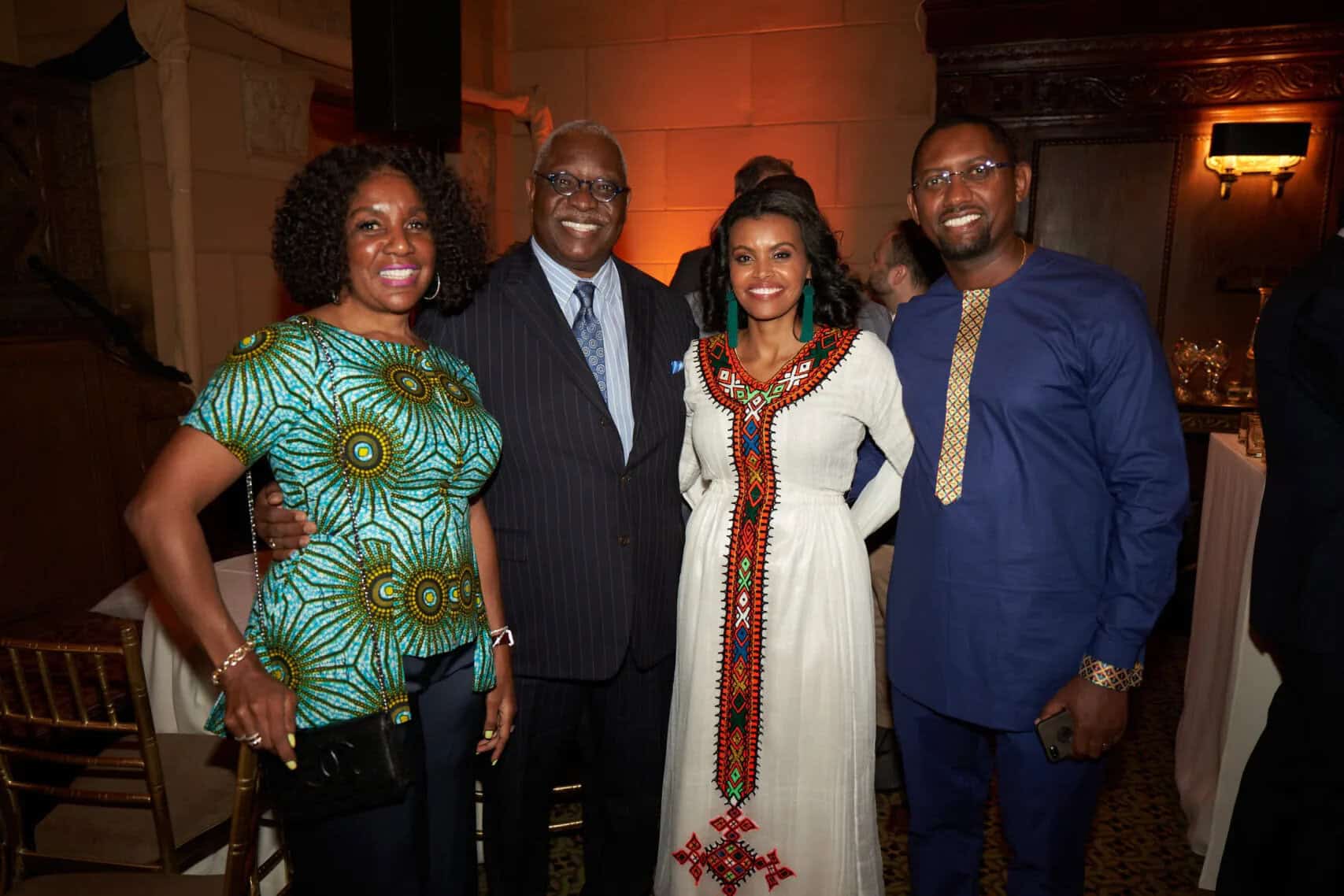A group of four smiling individuals at a cultural event, showcasing vibrant traditional and modern A.