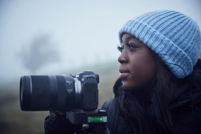 Young African woman using a camera outdoors, promoting skills and education.