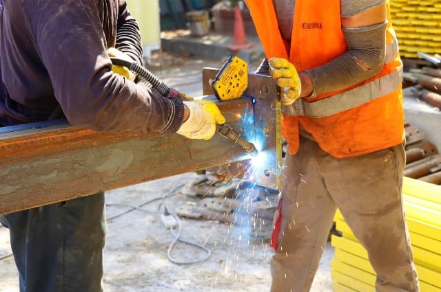 Workers welding steel beams during construction in Kenya for infrastructure development.