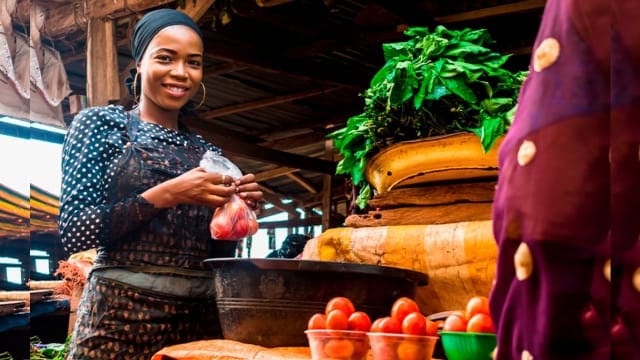 African woman selling fresh tomatoes at local market.