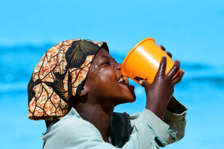 Woman drinking clean water from a container in Africa.