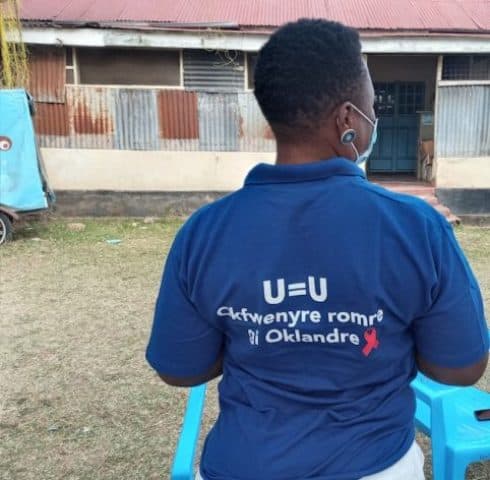 Woman wearing HIV awareness shirt at health outreach event in Africa.