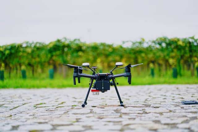 Drone flying over farmland with lush green crops in the background.