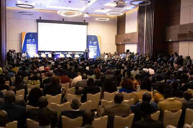 Large conference with attendees listening to a presentation on energy investments in Africa.