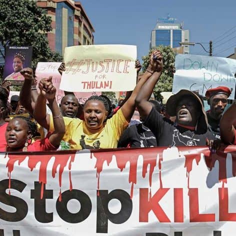 Protesters in Eswatini demand justice and end violence, holding signs and raising fists during a dem.