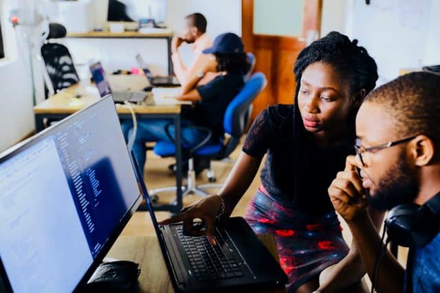 IT professionals working together on a computer in a modern office environment.