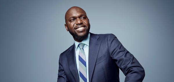 Larry Madowo, African journalist and host, smiling in a suit for African Voices Changemakers.
