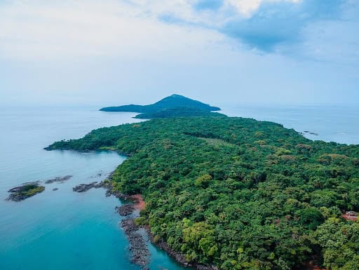 Aerial view of Lion Mountain surrounded by lush green forest and Atlantic Ocean in Sierra Leone.