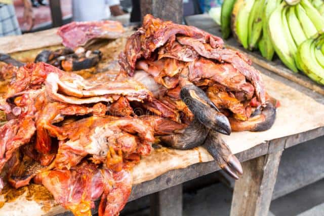 Bushmeat market in Kenya with fresh wild animal meat and bananas in the background.