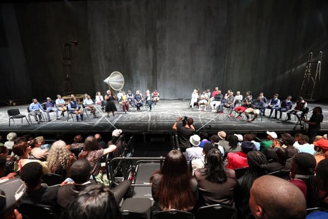 Audience watching a theatrical performance with William Kentridge and young South Africans on stage.