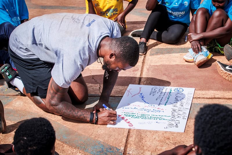 Community leader signs pledge against NTDs at Rwanda basketball event.