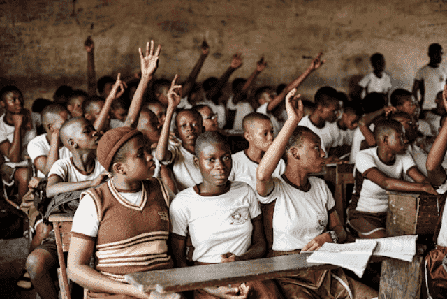 African students in classroom raising hands during lesson.