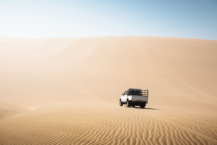 Exploring Namibia's vast desert with a 4x4 vehicle amidst golden sand dunes.